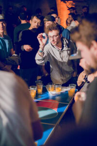 Man throwing ping pong ball, following the rules of Beer Pong.