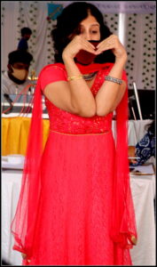 Woman in red dress acting out heart gesture during Charades game rules