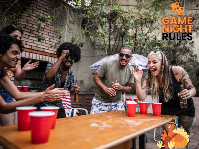 Friends playing turkey pong drinking game outdoors at Friendsgiving party with red cups on wooden table in backyard setting